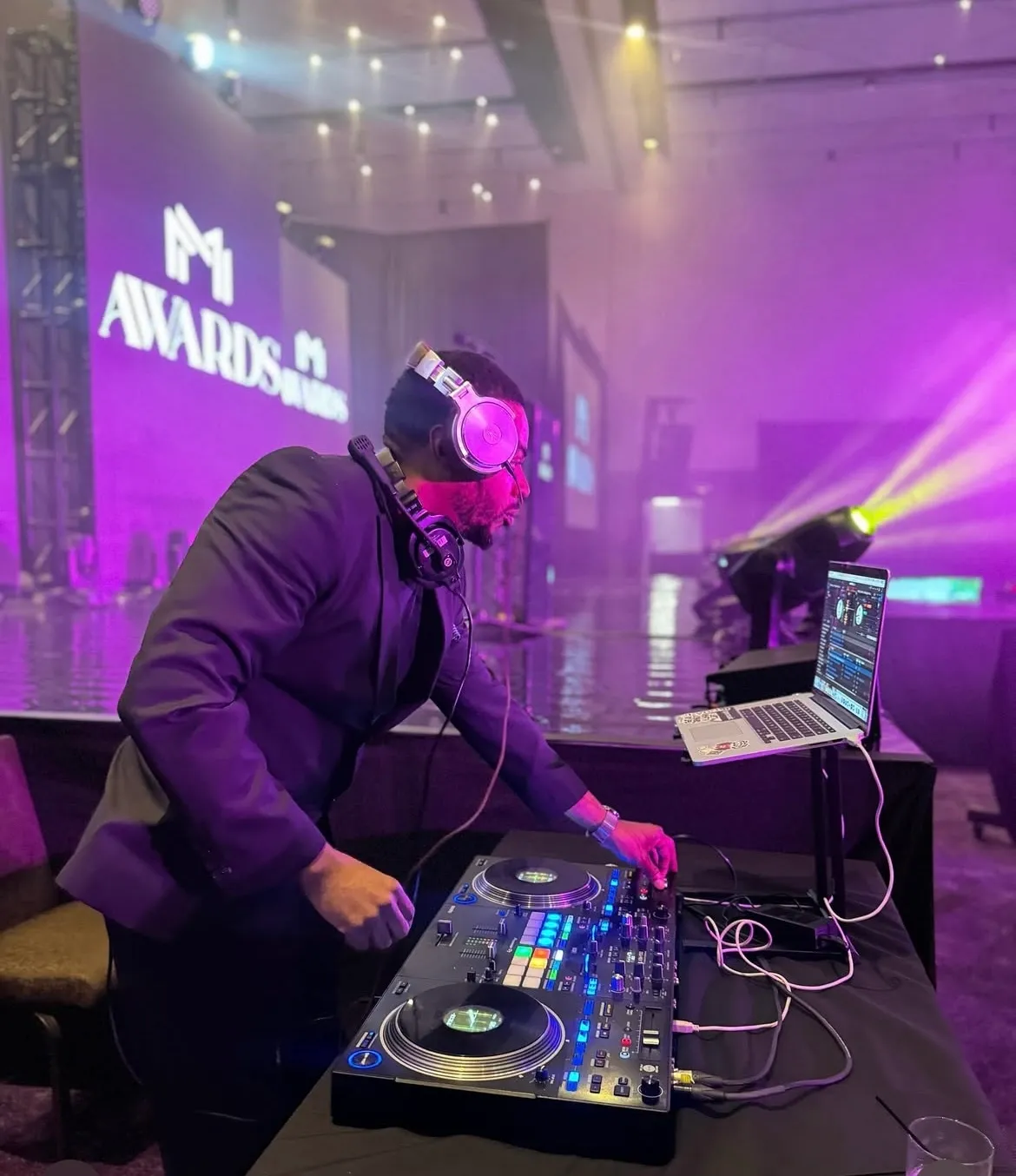 DJ Battio performing beside a conference awards stage
